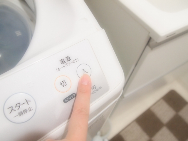 洗濯機のボタンを押す